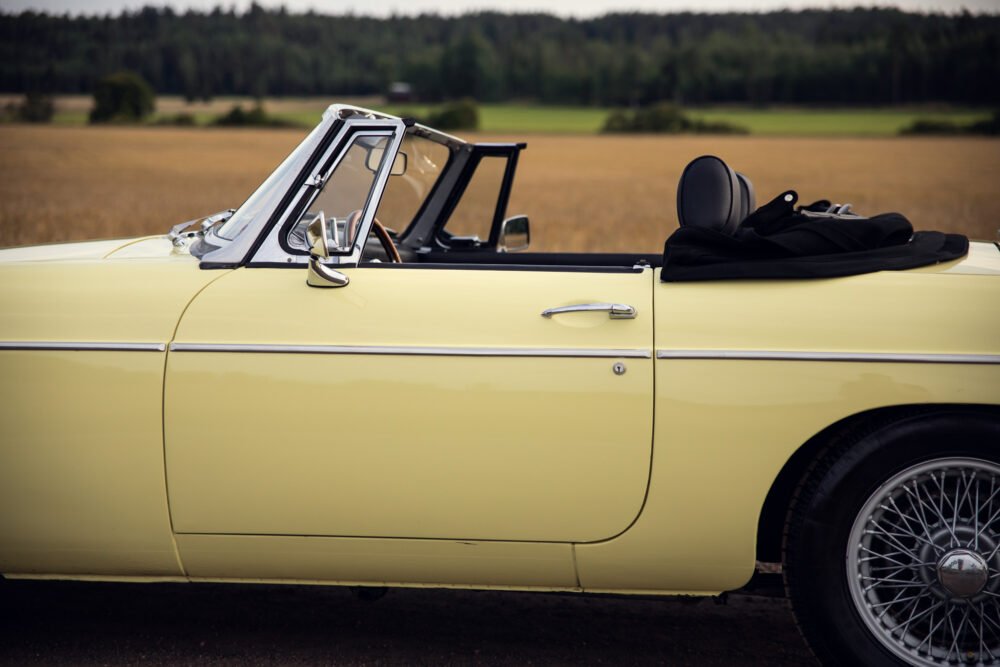 Yellow vintage convertible car in rural setting.