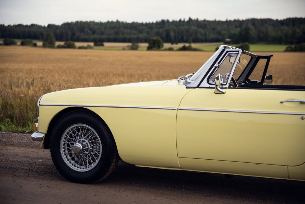 Yellow classic convertible car alongside golden wheat field.