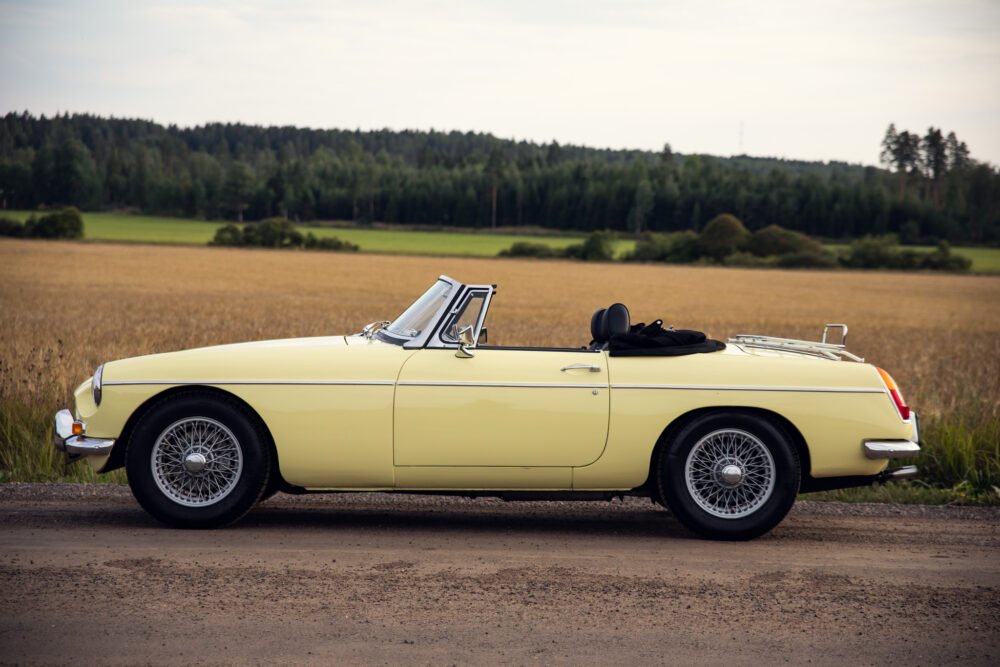 Vintage yellow convertible car parked beside golden wheat field.