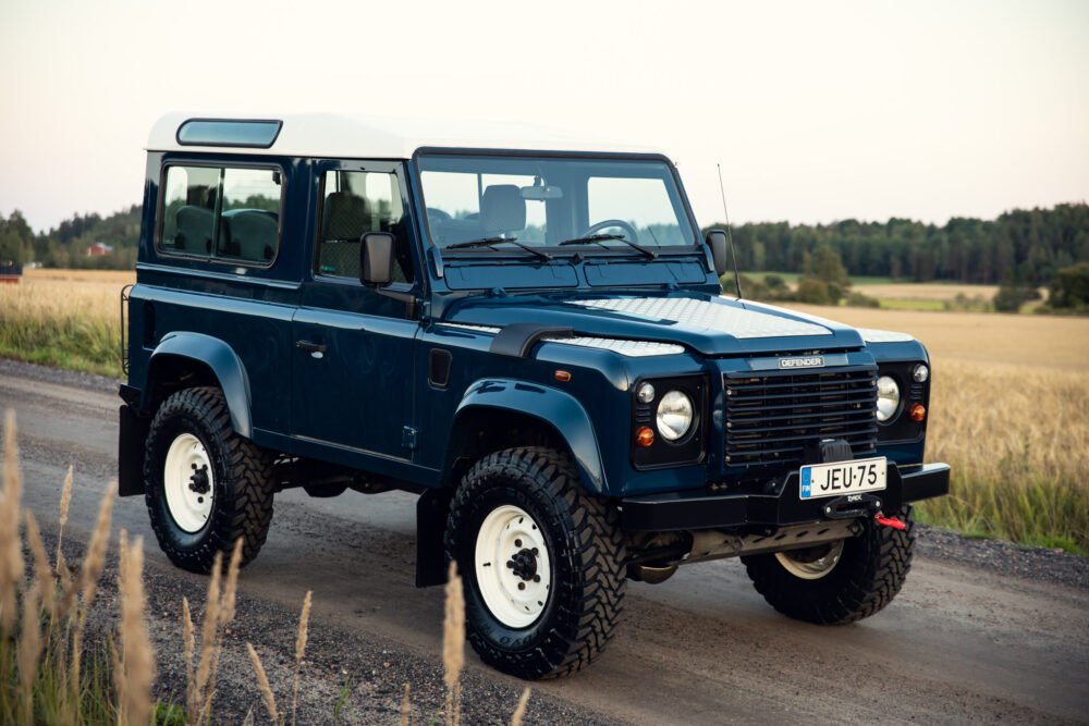 Blue Land Rover Defender on rural road.