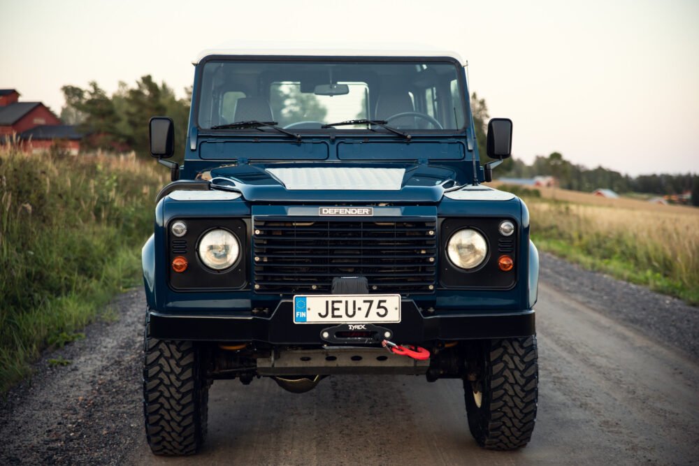 Blue Land Rover Defender on rural road.