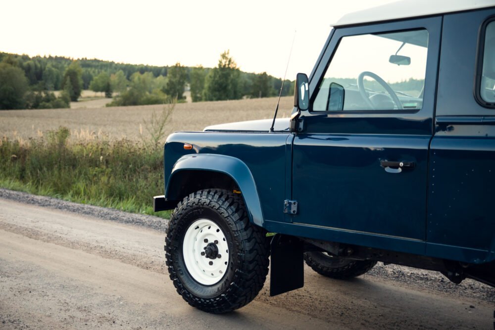 Blue SUV on rural dirt road at dusk.