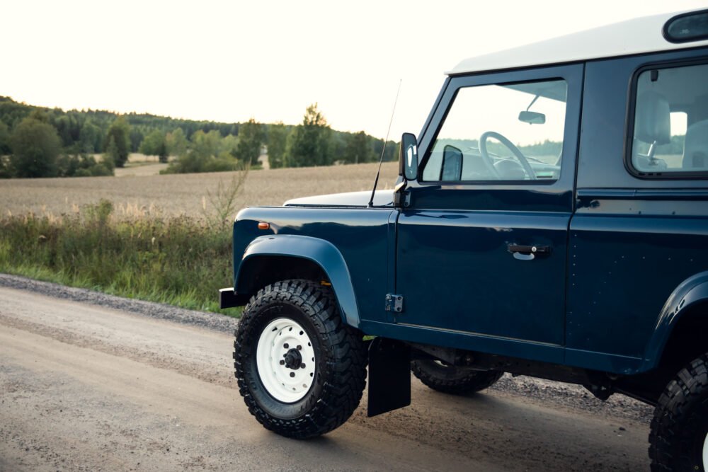 Blue SUV on rural road at dusk.