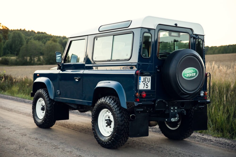 Blue Land Rover Defender on country road.