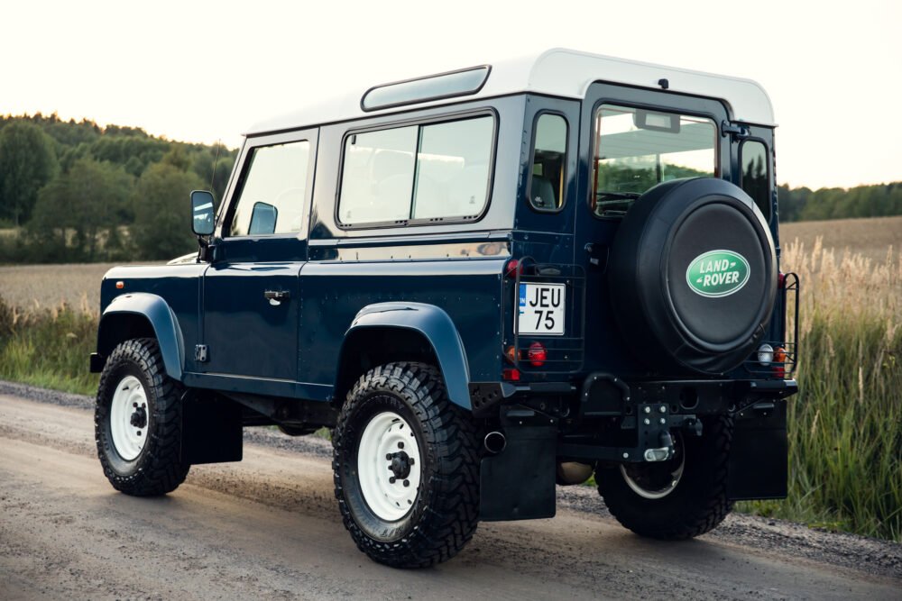 Blue Land Rover Defender on country road.