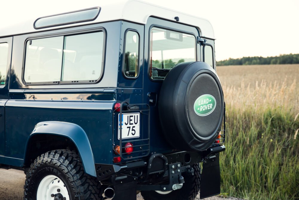 Blue Land Rover Defender near a field.