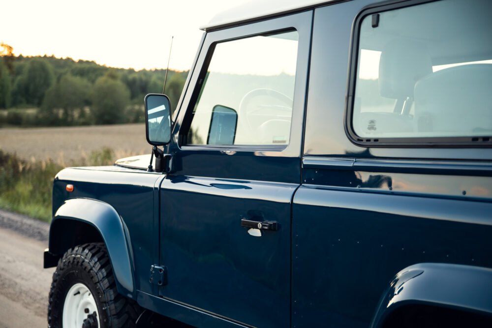 Blue SUV parked in countryside at sunset.