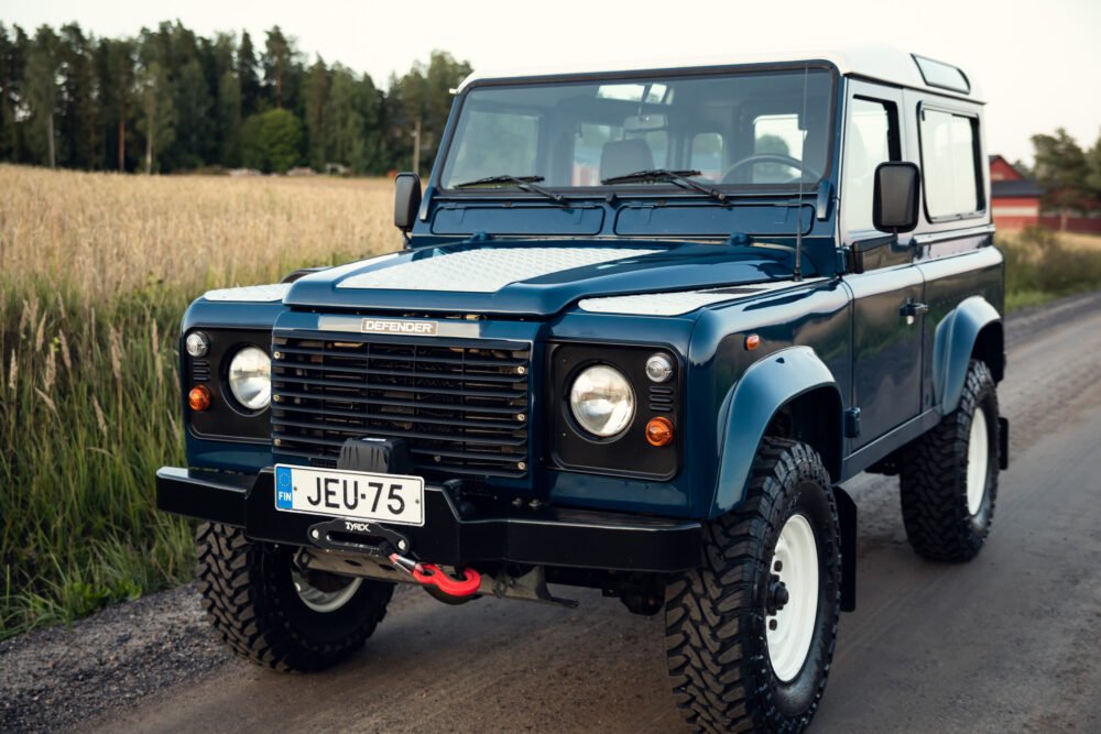 Blue Land Rover Defender on rural road.