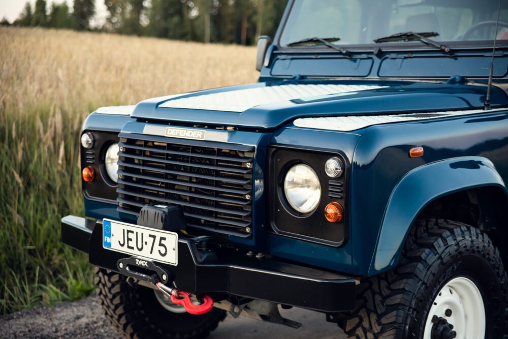 Blue Land Rover Defender in a field at dusk.