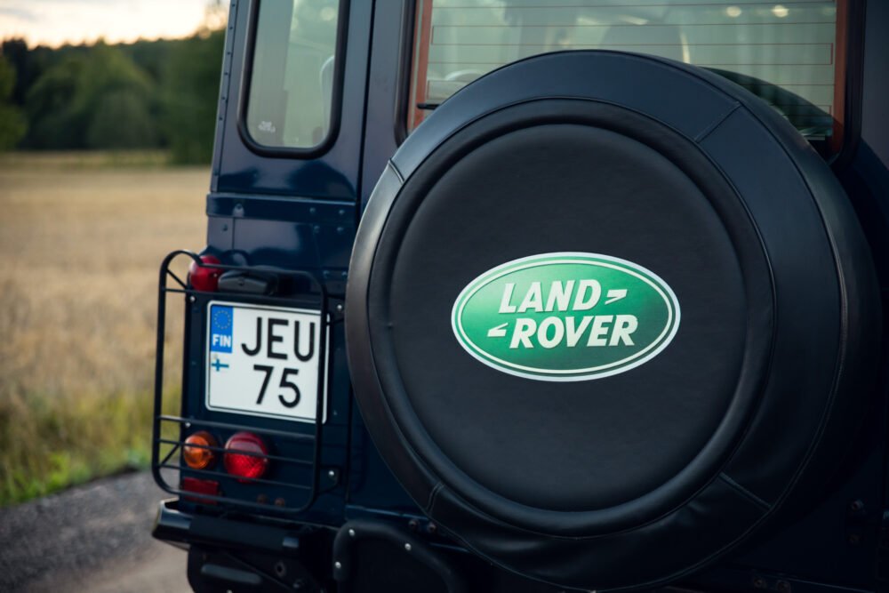 Land Rover spare tire cover on vehicle in countryside.