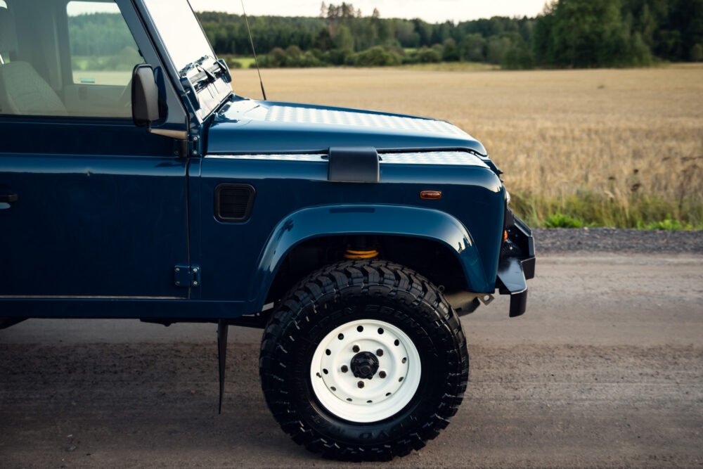 Blue off-road vehicle parked beside country road.