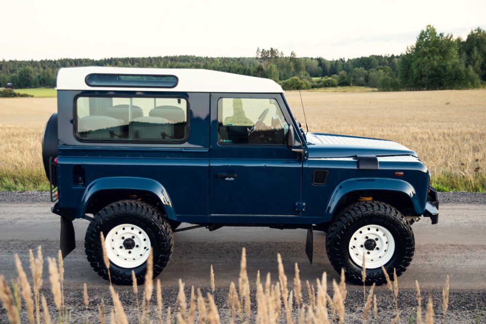 Blue SUV parked on rural road near wheat field.