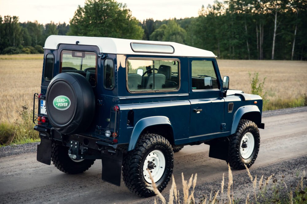 Blue Land Rover Defender on rural road.