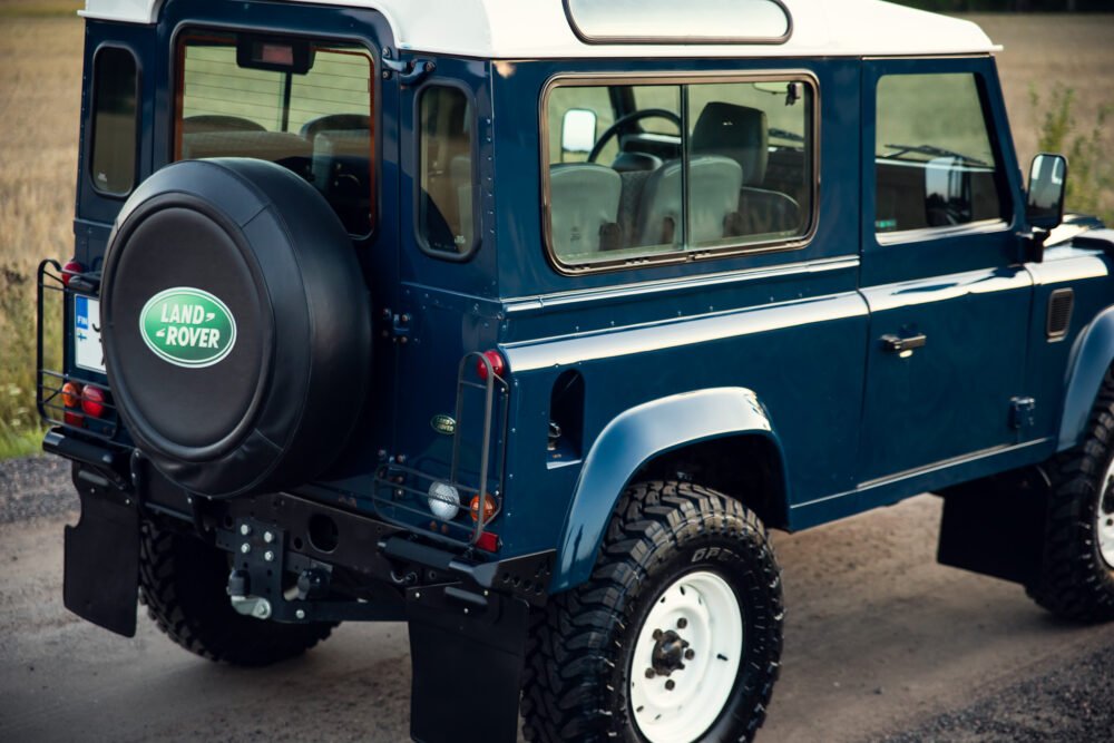 Blue Land Rover Defender on rural road.