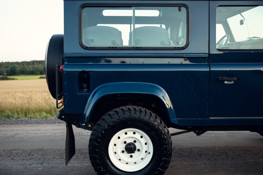 Blue SUV on rural road, side and tire details shown.