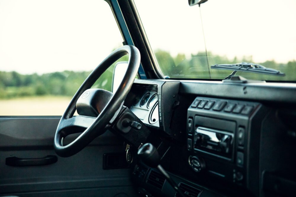 Interior view of old car with steering wheel and dashboard.