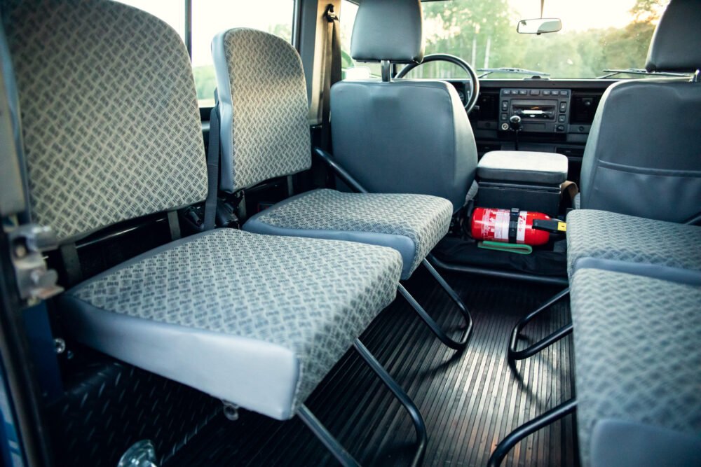 Interior of a van with patterned seats and fire extinguisher.