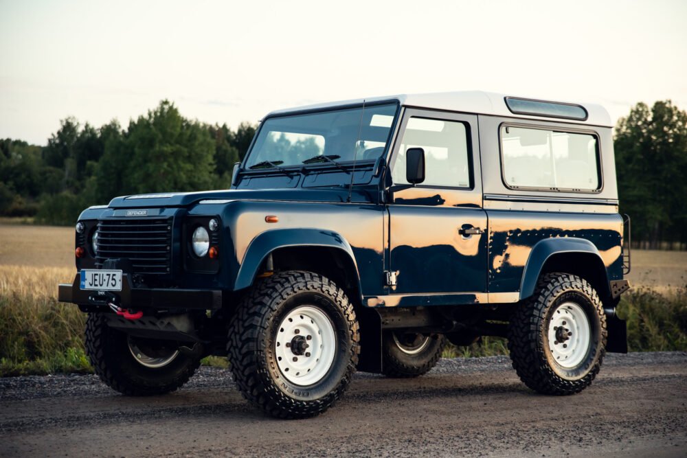 Blue Land Rover Defender parked on a country road.