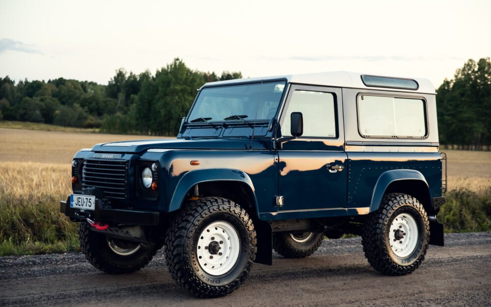 Blue off-road SUV parked in rural landscape.