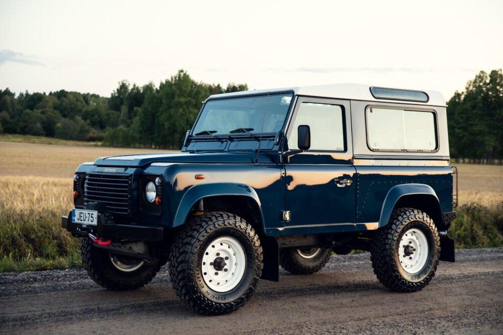 Blue off-road SUV parked in rural landscape.