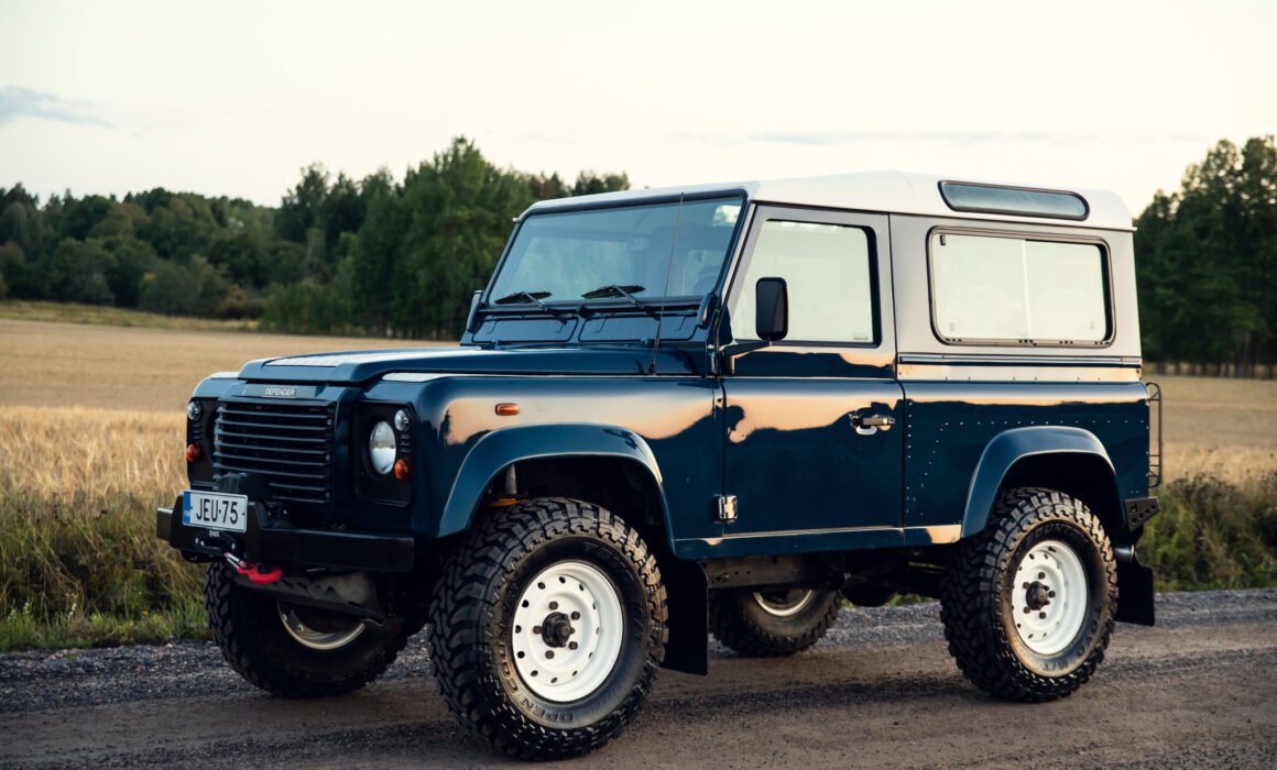 Blue off-road SUV parked in rural landscape.