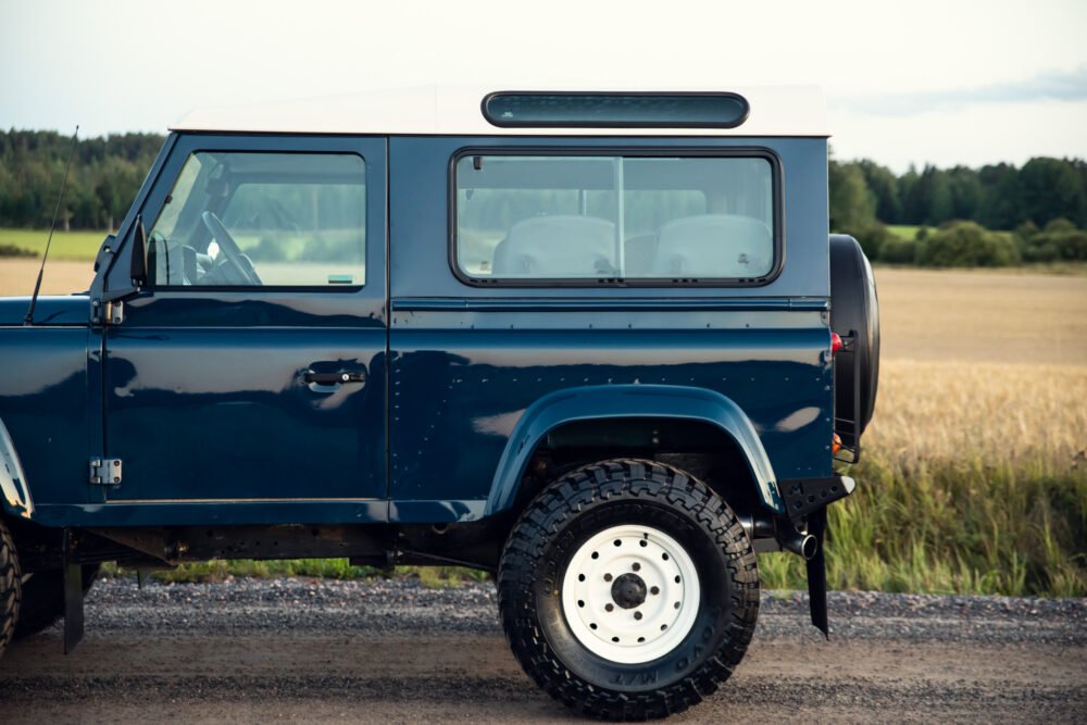 Blue off-road vehicle parked beside farmland.