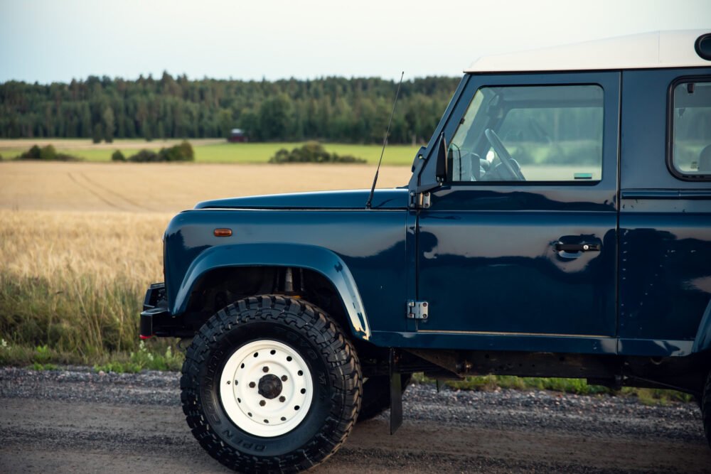 Blue off-road vehicle parked near golden wheat field.