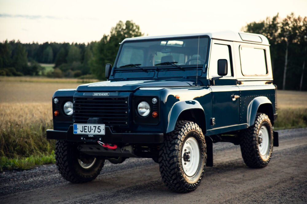 Blue Land Rover Defender on a country road.