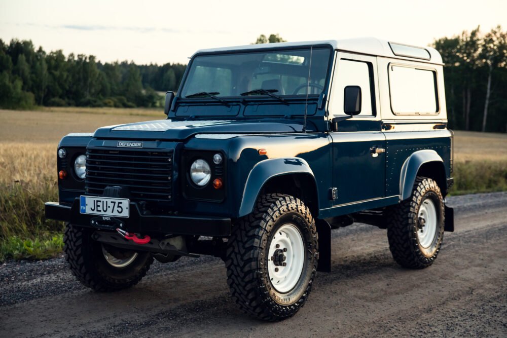 Blue Land Rover Defender on rural road.