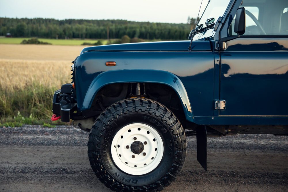 Blue off-road vehicle parked beside wheat field.