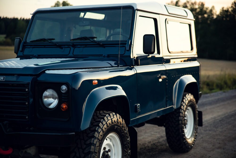 Blue off-road vehicle on a rural road at dusk.