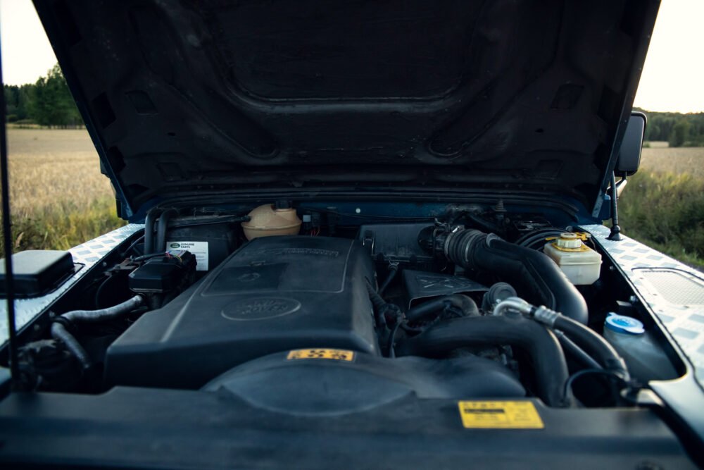 Car engine compartment close-up, open hood, outdoor setting.