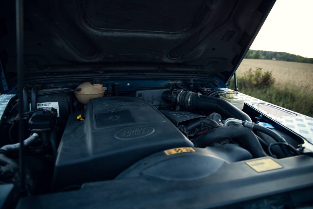 Land Rover engine compartment, hood open in field.