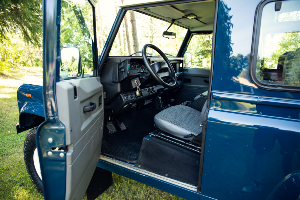Blue SUV interior with open door in nature.