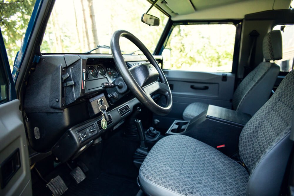 Vintage car interior with steering wheel and patterned seats.