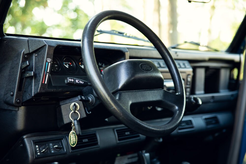 Vintage Land Rover interior with steering wheel and dashboard.