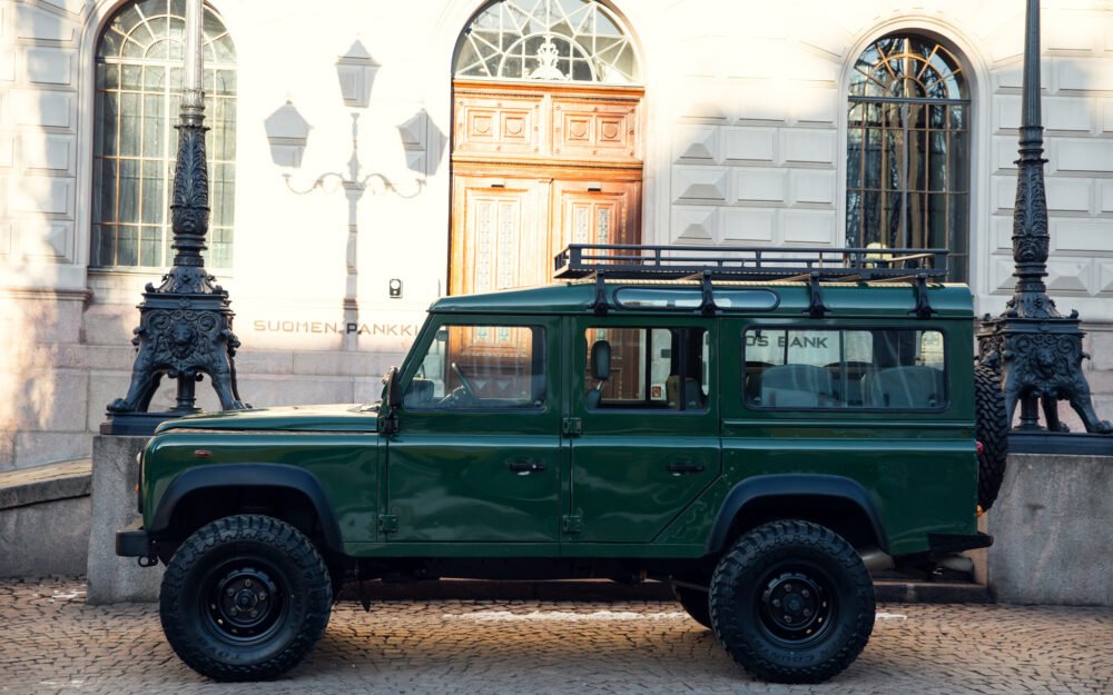 Green SUV parked outside a historic building.