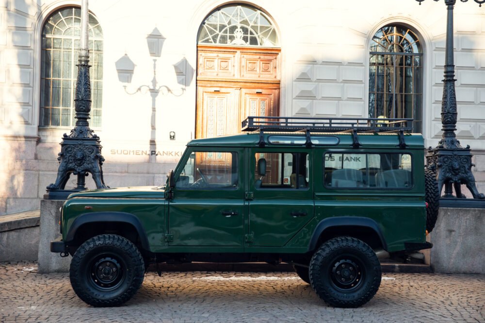 Green SUV parked outside a historic building.