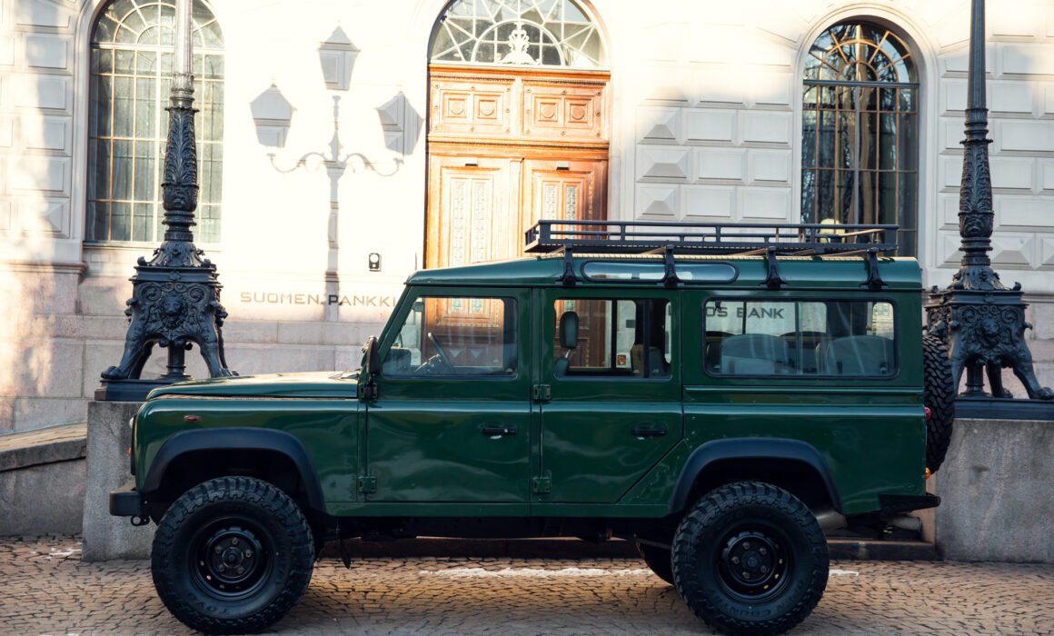 Green SUV parked outside a historic building.