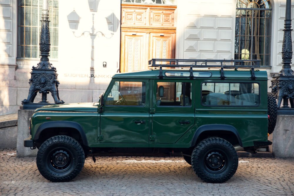 Green SUV parked near historic building and ornate lamps.