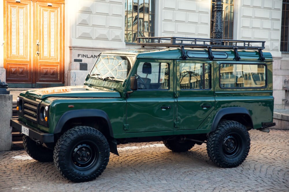 Green Land Rover Defender parked in urban setting.