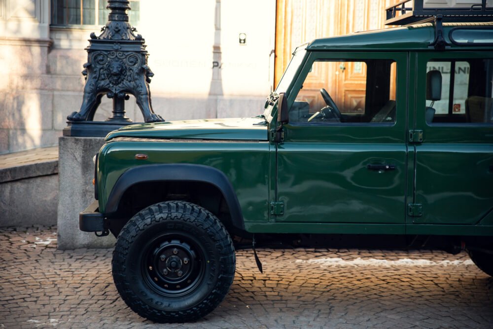 Green off-road vehicle parked near ornate street lamp.