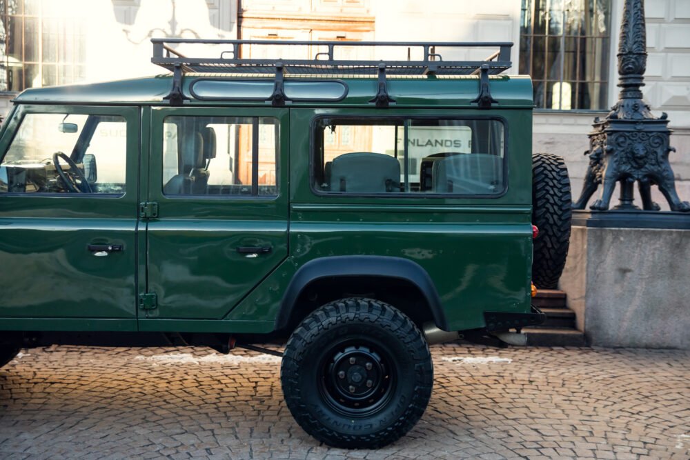 Green off-road SUV parked near historic building.