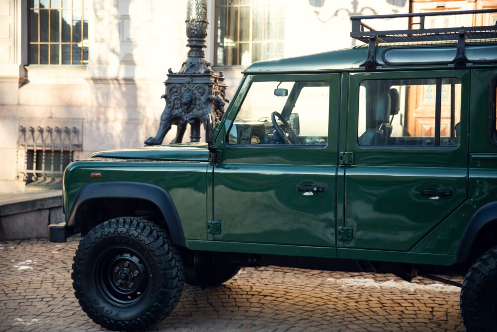 Green SUV parked near historic statue and building.