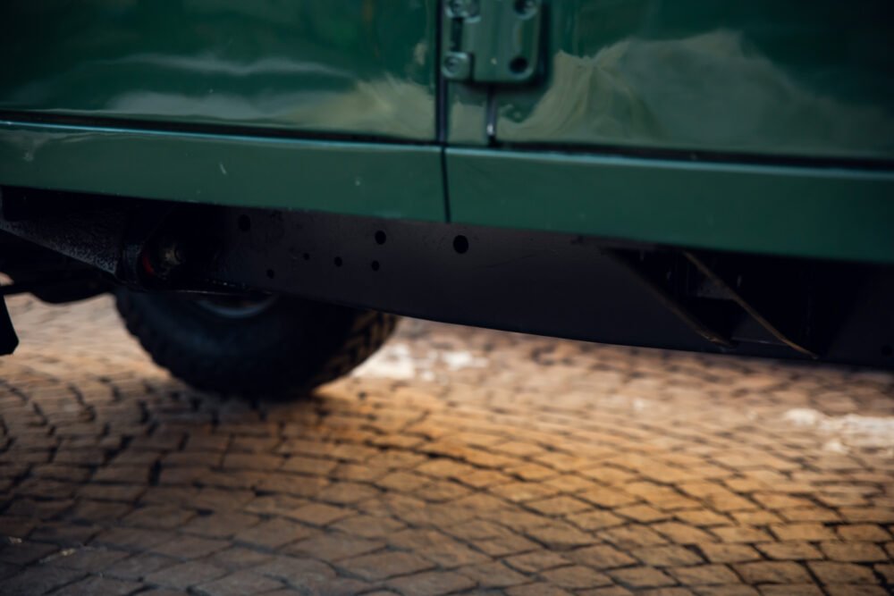 Close-up of green vehicle's side on cobblestone street.