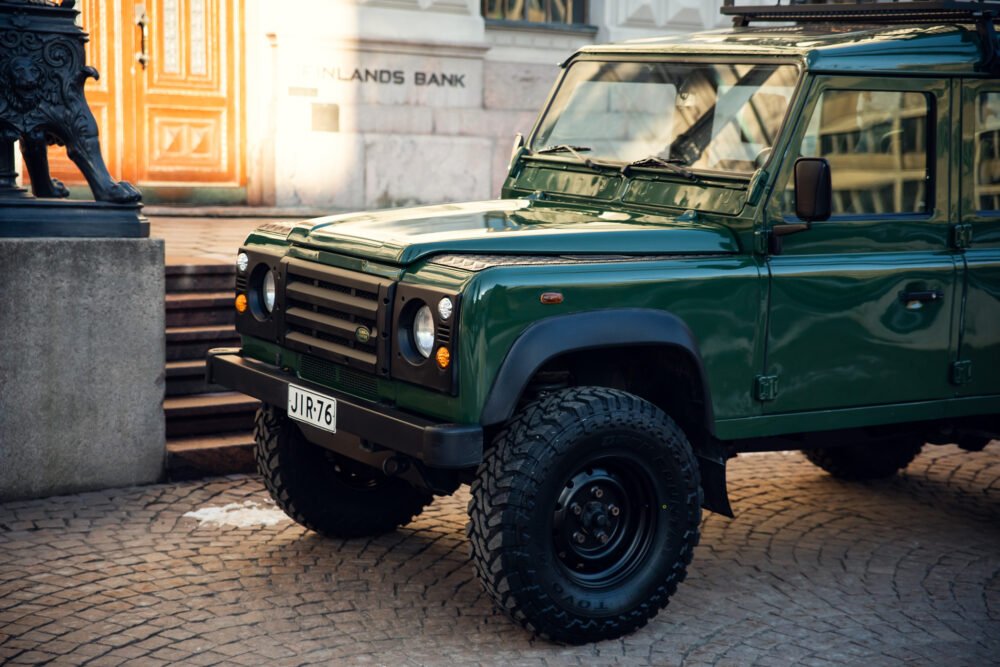 Green off-road vehicle parked near historic building.