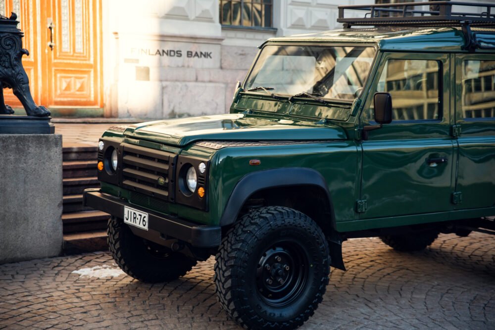 Green SUV parked outside historic building.