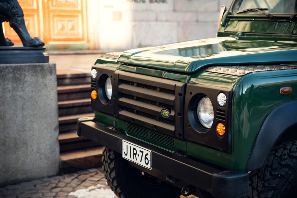 Green Land Rover Defender parked near historic building.