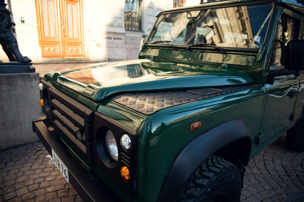 Green SUV parked in urban setting near historical building.