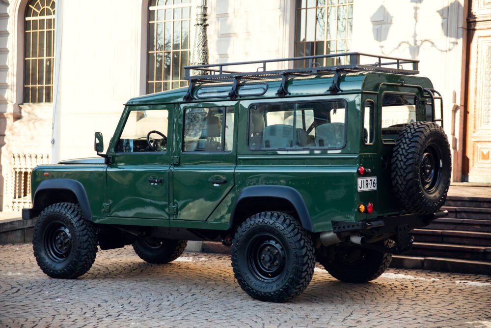 Green off-road SUV parked near historic building.